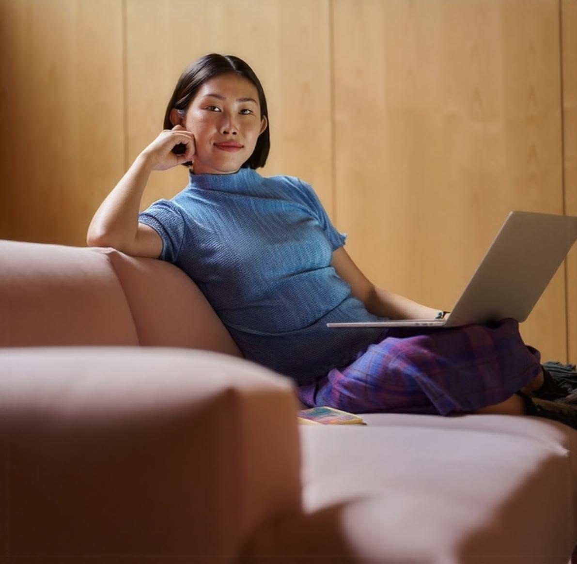 Small business owner relaxing on a couch with her laptop, smiling at the camera